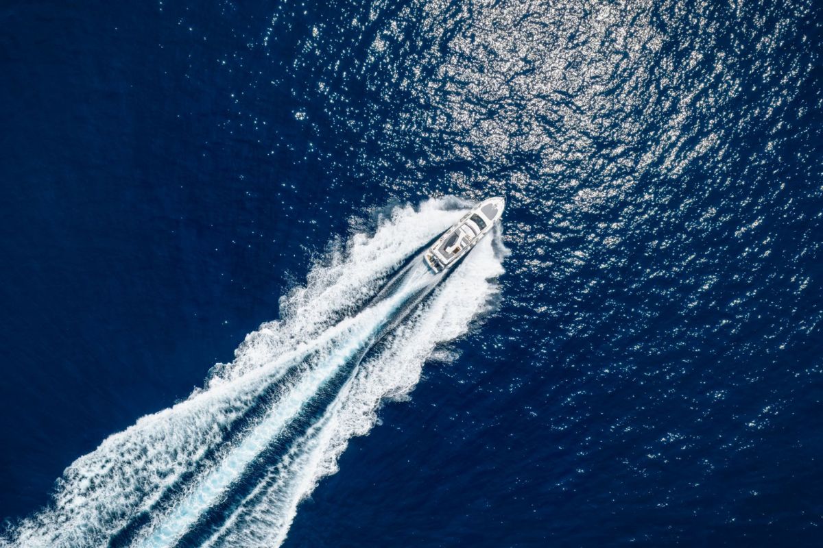 An aerial view of a yacht speeding across the ocean.