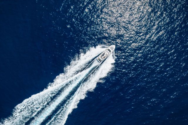 An aerial view of a yacht speeding across the ocean.