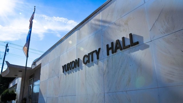Exterior view of Yukon City Hall with a flag and clear blue sky in the background.