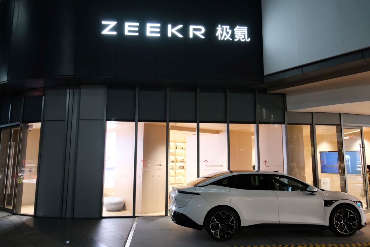 A white electric car parked outside a ZEEKR storefront at night.