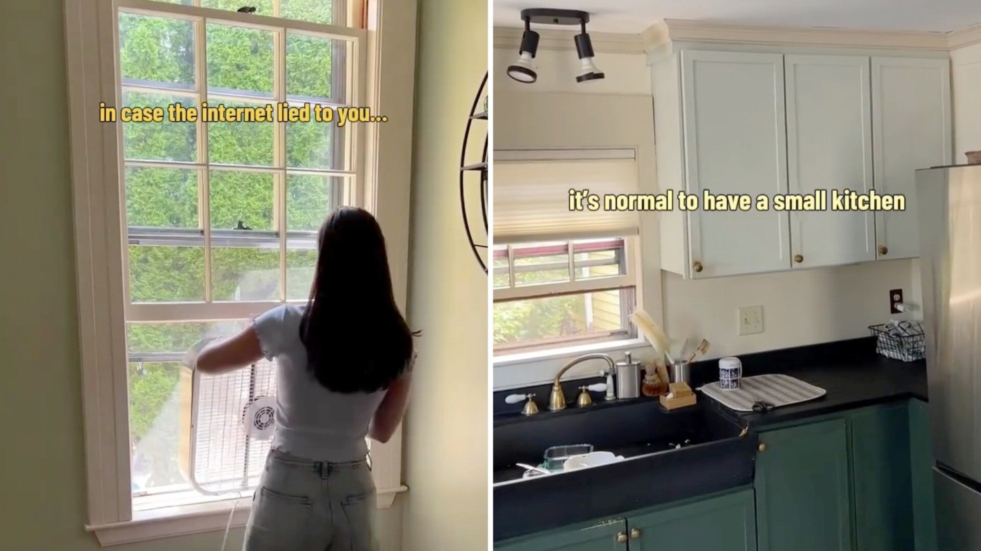 A person with long hair removes a fan from a window while showcasing a small kitchen on the other side.