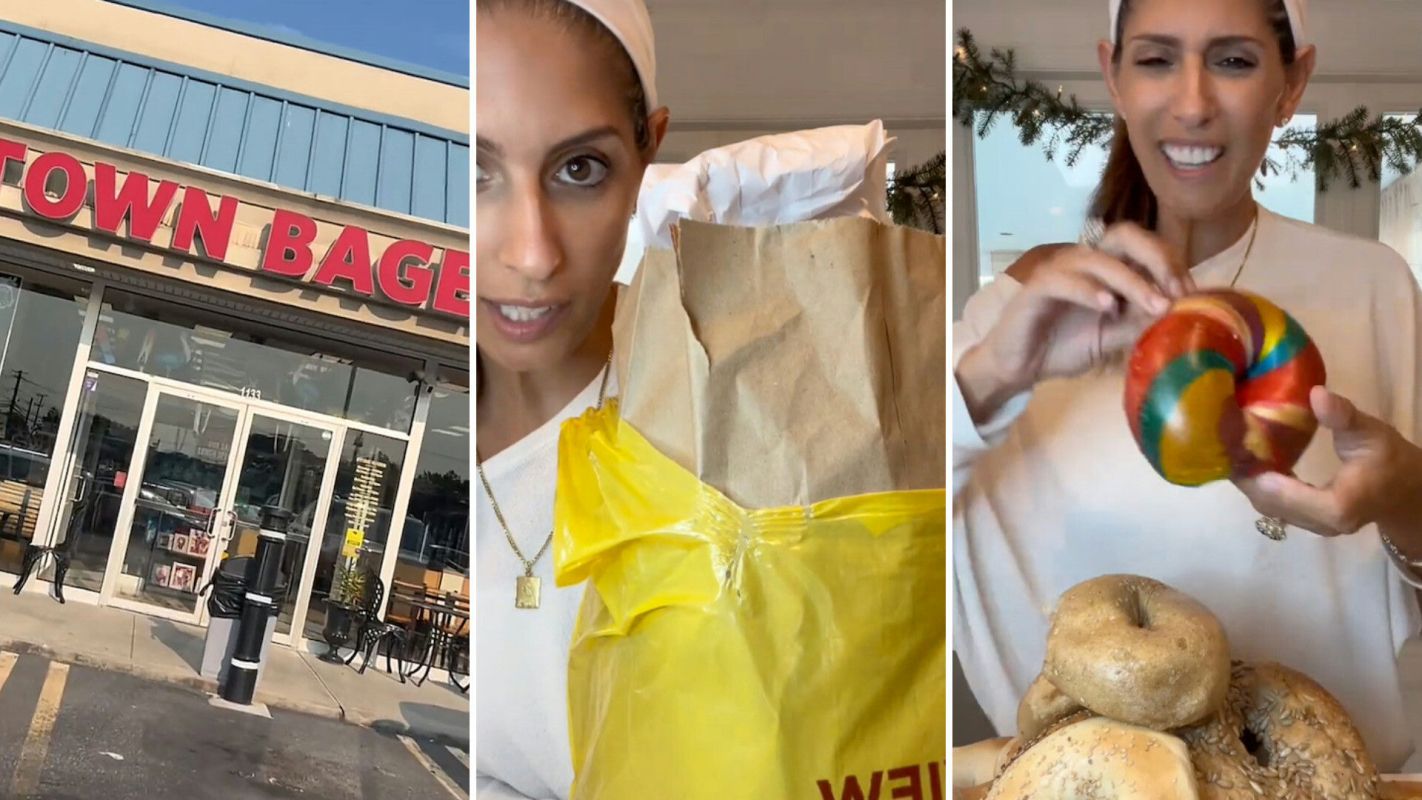 A storefront with a sign that reads "Town Bagel," and a woman holding a bag and colorful bagels.