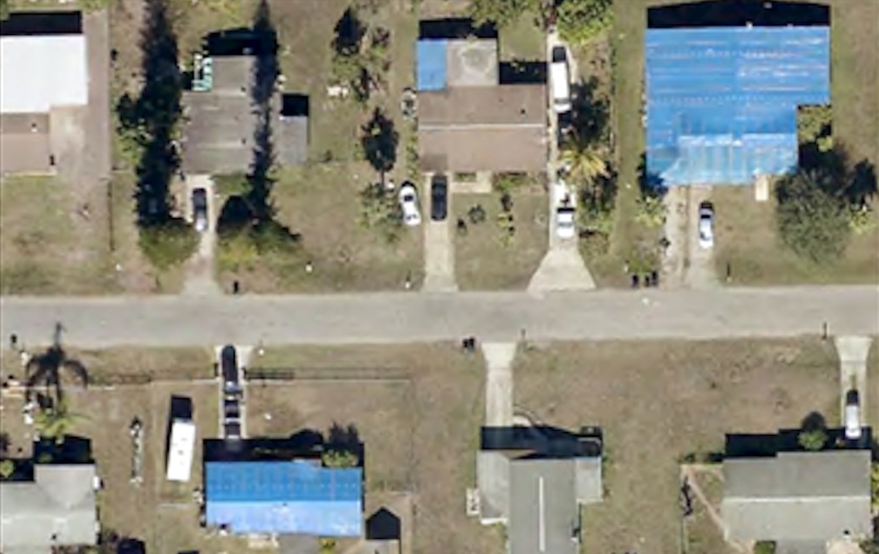 Aerial footage of a neighborhood with storm-damaged roofs.
