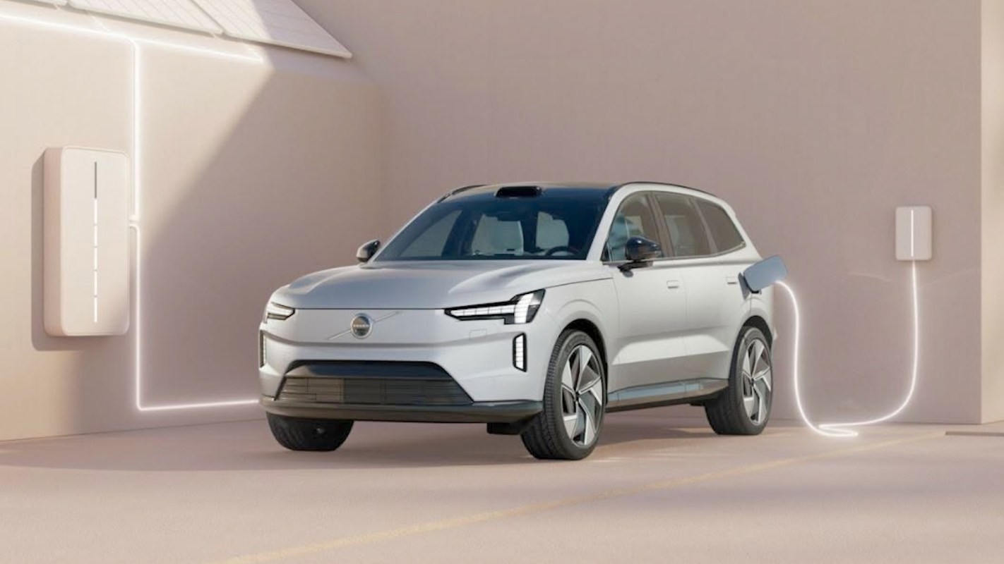 An electric vehicle charging next to a wall-mounted charger with solar panels above.