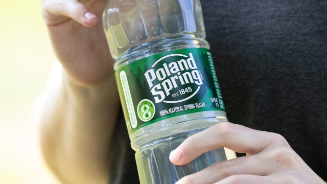 A person holding a bottle of Poland Spring water.