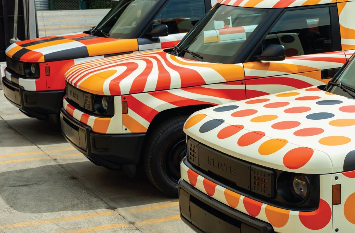 Three vehicles with colorful, patterned wraps featuring stripes and polka dots parked in a lot.