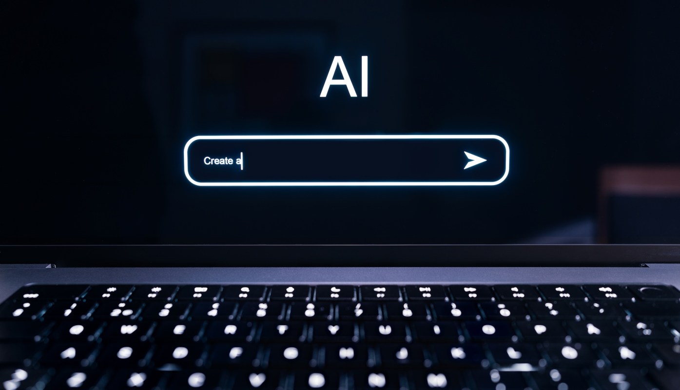 A laptop screen displays the text "AI" and a prompt field labeled "Create a."