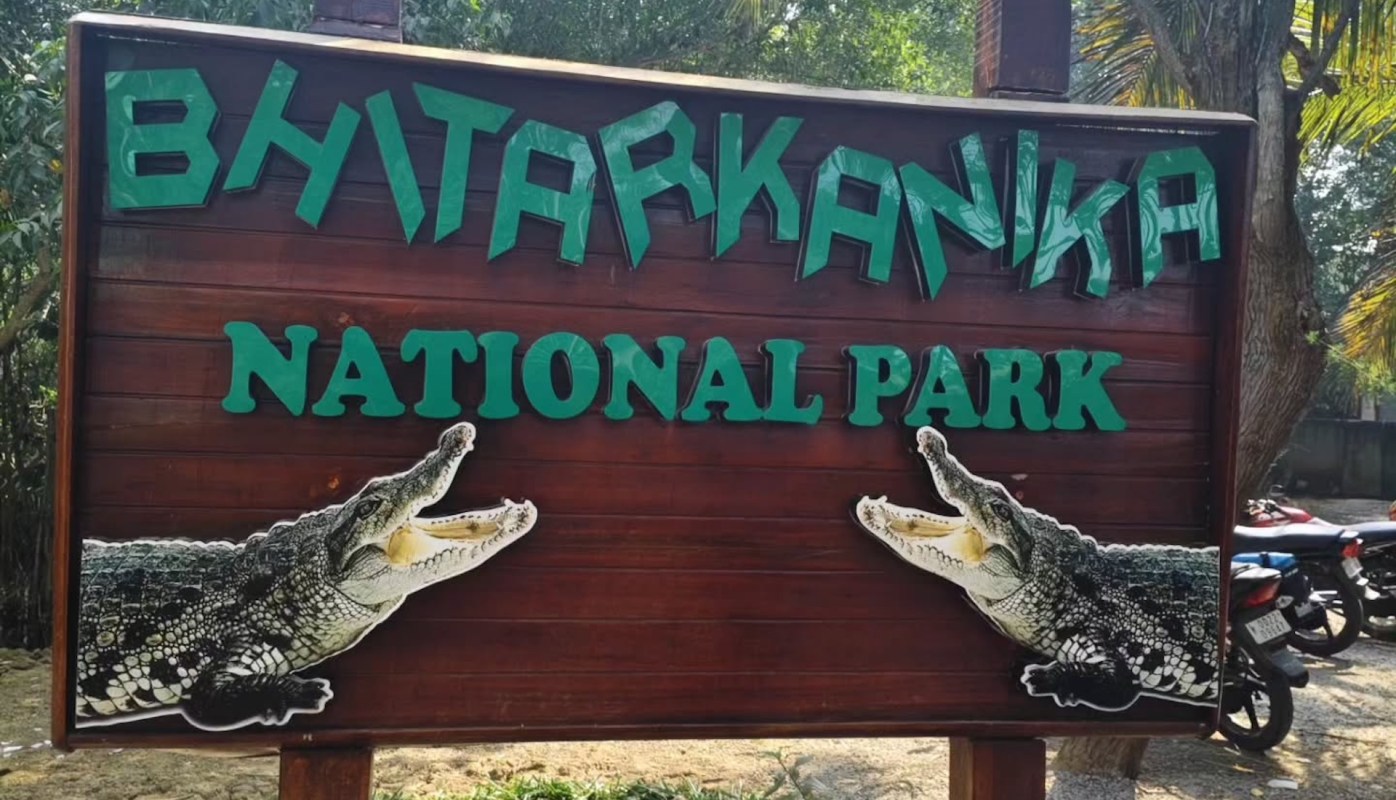 A wooden sign displaying "Bhitarkanika National Park" with crocodile illustrations on either side.