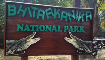 A wooden sign displaying "Bhitarkanika National Park" with crocodile illustrations on either side.