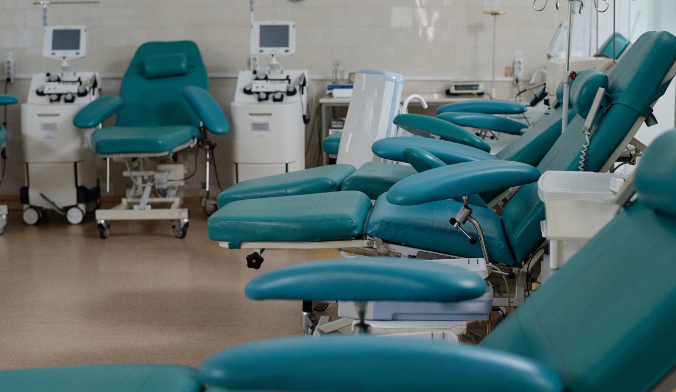 A medical facility with multiple teal examination chairs and equipment.
