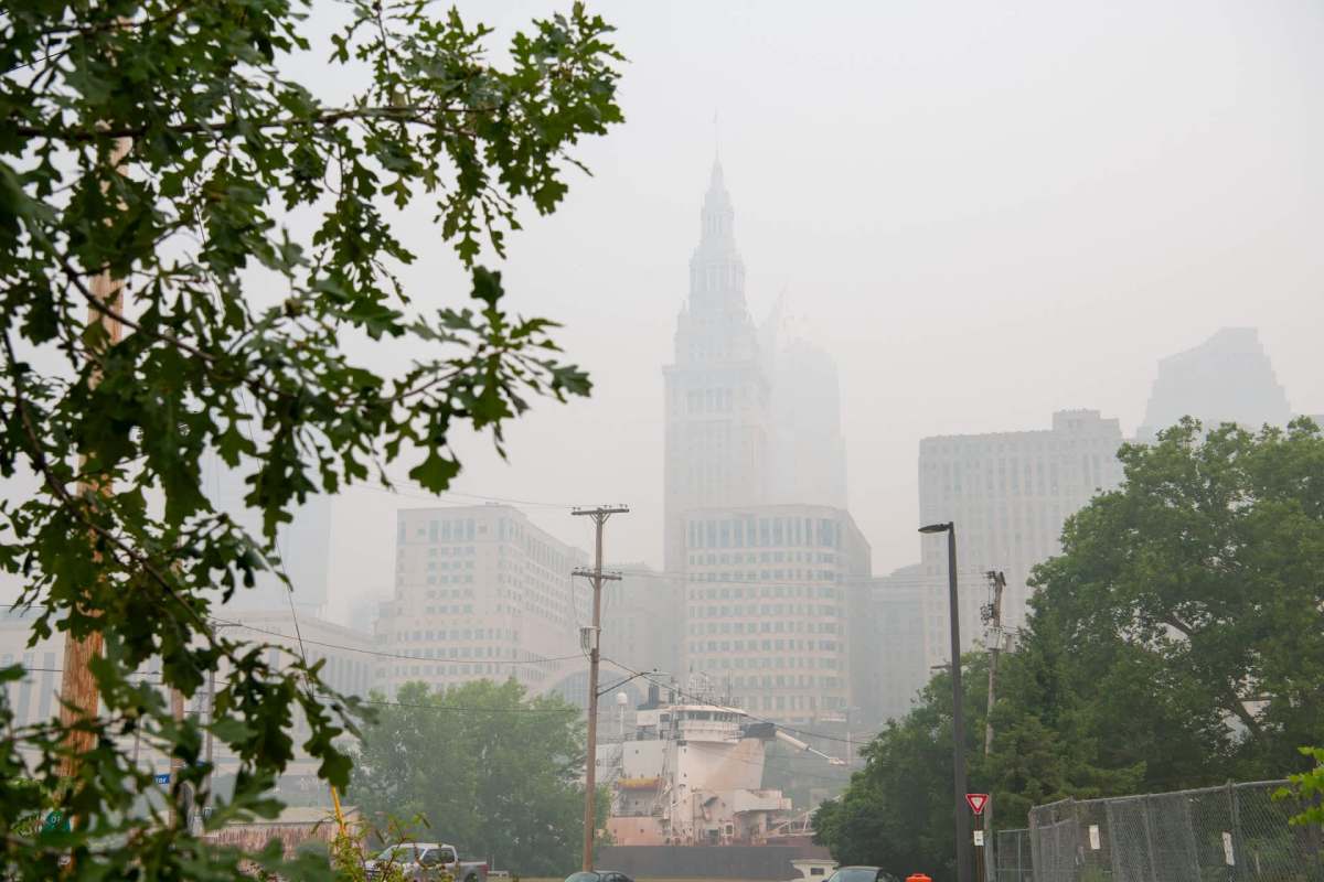 The Cleveland, Ohio, skyline partially obscured by smoke, featuring visible buildings and a ship docked in the foreground.