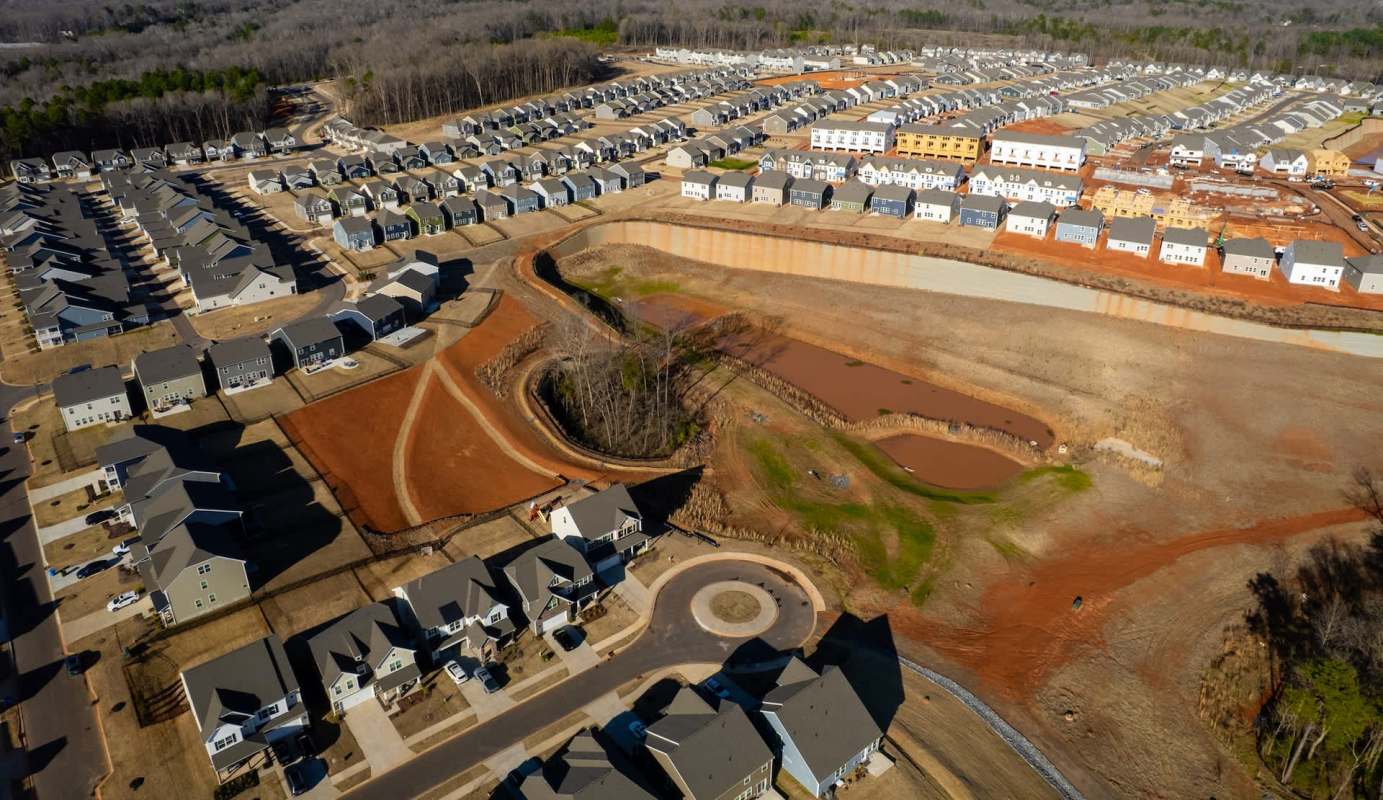 Aerial view of a residential area with houses, construction sites, and cleared land.