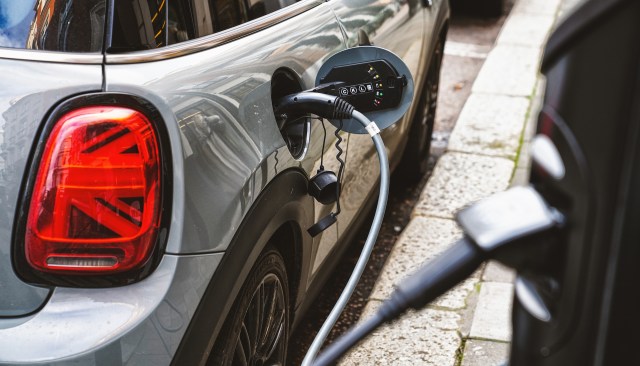 An electric car is charging at a charging station on a city street.