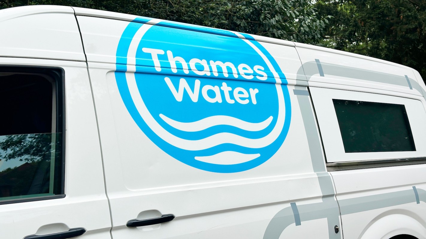 A van with a blue Thames Water logo and a window, parked near greenery.