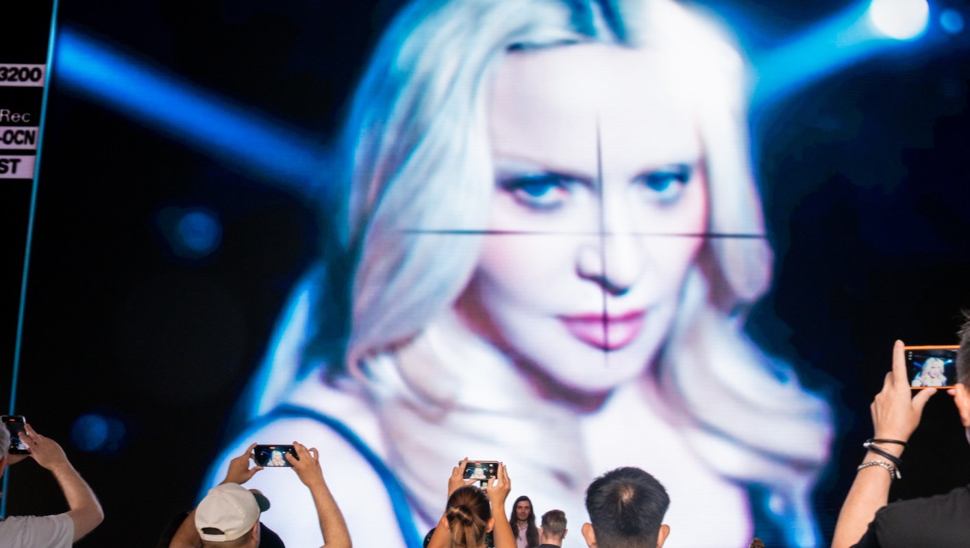 The singer Madonna being displayed on a video screen, with people with camera filming it.