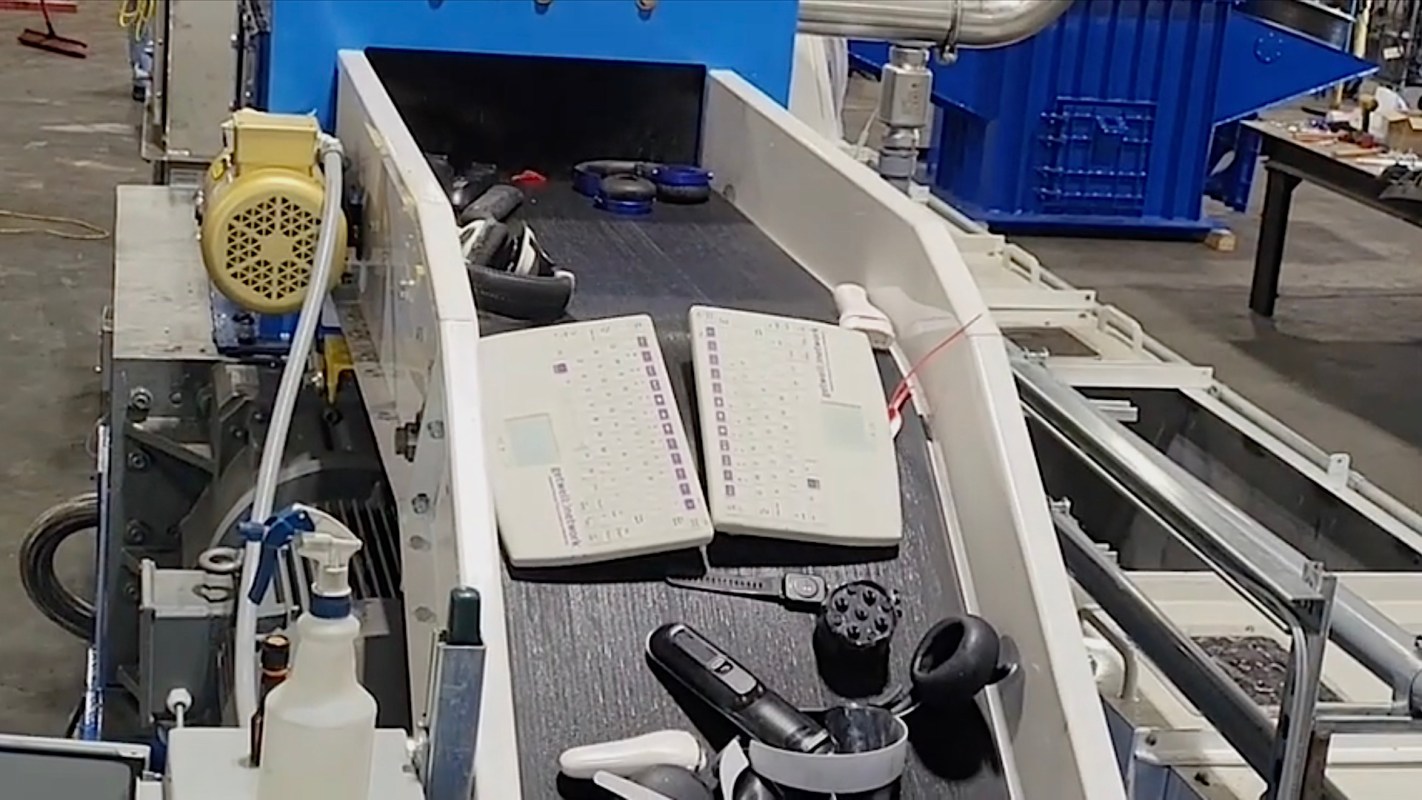 A conveyor belt with two keyboards and various electronic devices in a warehouse setting.