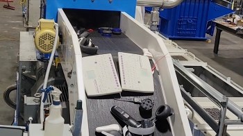 A conveyor belt with two keyboards and various electronic devices in a warehouse setting.