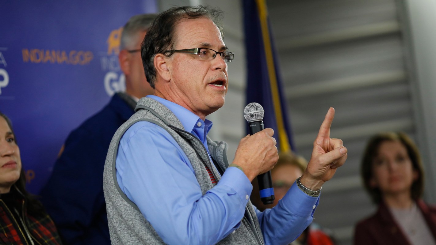 Indiana governor Mike Braun speaks into a microphone during a public event with an audience in the background.