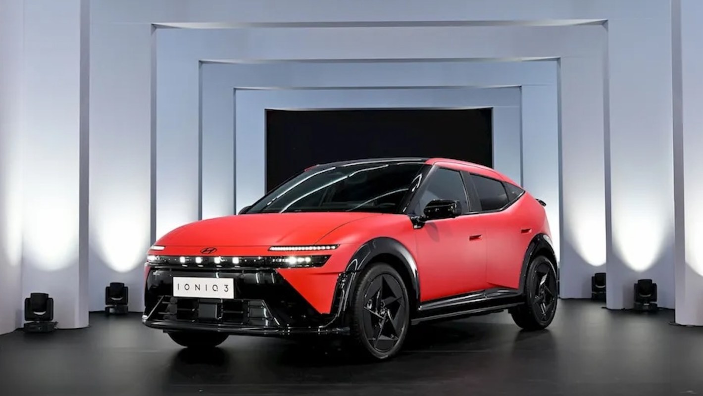 A red Hyundai Ioniq 3 electric car displayed on a stage with white columns and spotlighting.