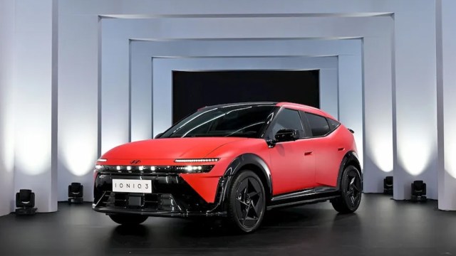 A red Hyundai Ioniq 3 electric car displayed on a stage with white columns and spotlighting.