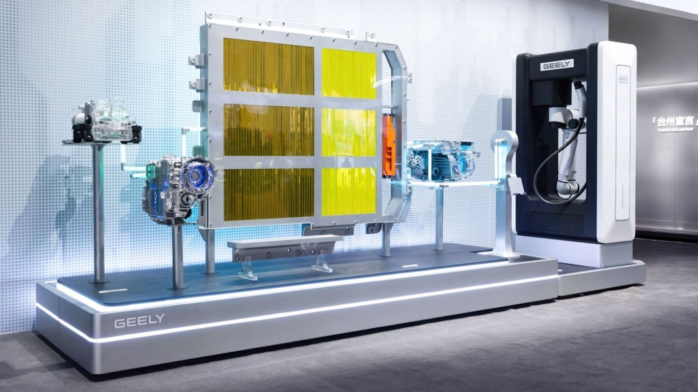 A display of automotive battery technology featuring components and a robotic charger labeled "GEELY."
