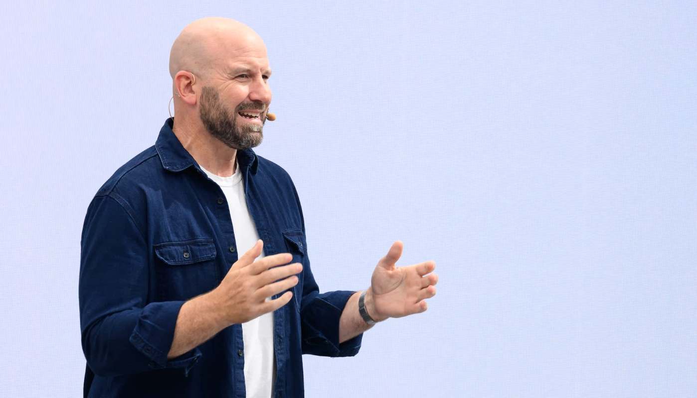 Andrew Bosworth, chief technology officer of Meta, speaks on stage with a microphone headset in front of a light background.