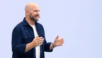 Andrew Bosworth, chief technology officer of Meta, speaks on stage with a microphone headset in front of a light background.