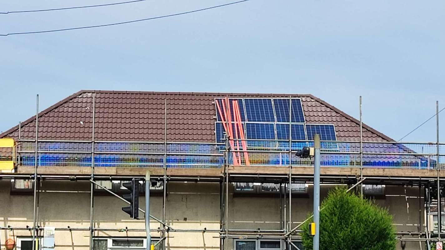A house undergoing construction with scaffolding and solar panels installed on the roof.