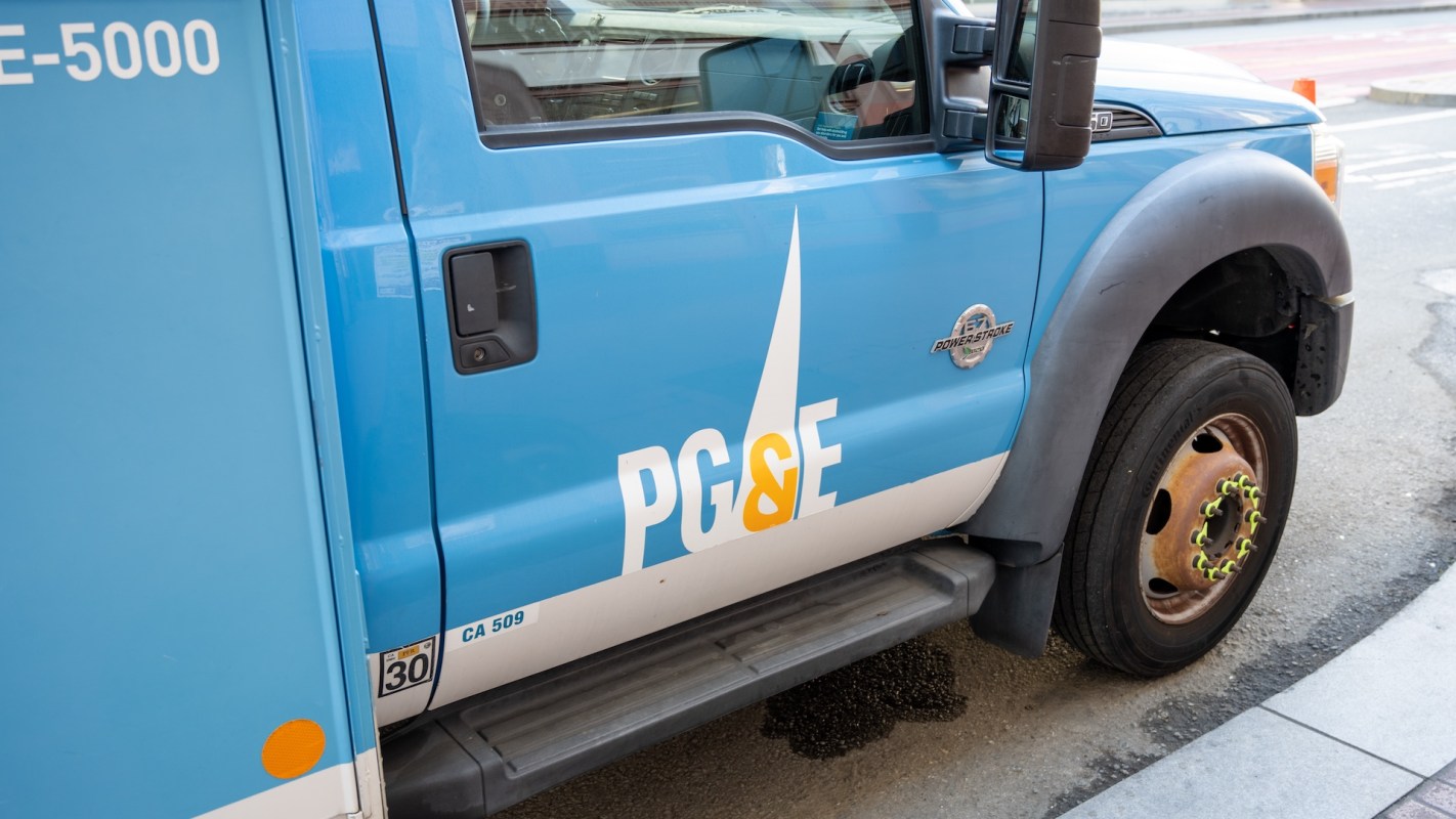 A blue utility truck with a PG&E logo parked on the street.