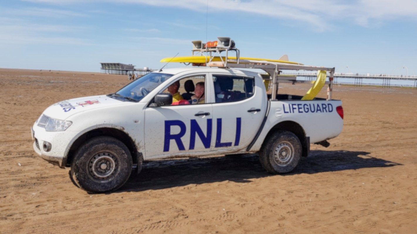 An RNLI lifeguard truck on a beach.