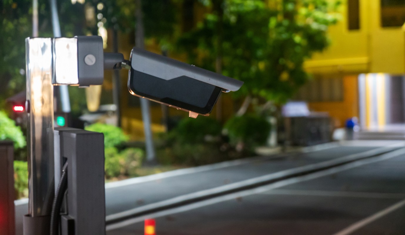 A security camera mounted near a parking area at night.