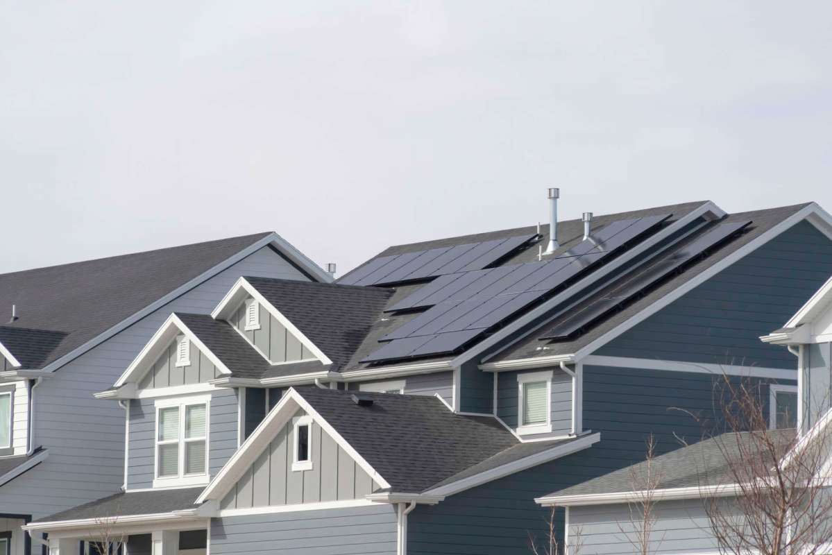 A residential area with houses featuring solar panels on the roofs.