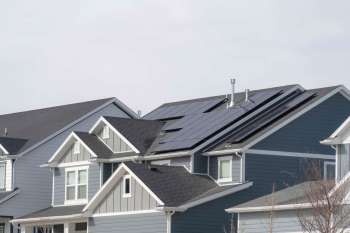 A residential area with houses featuring solar panels on the roofs.