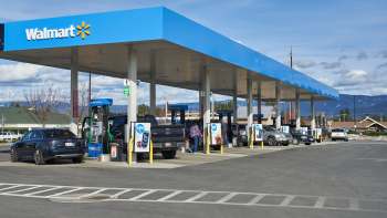 A Walmart gas station with multiple fuel pumps and vehicles in a parking lot.