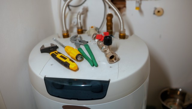 A water heater with various tools, including wrenches and pliers, on top.