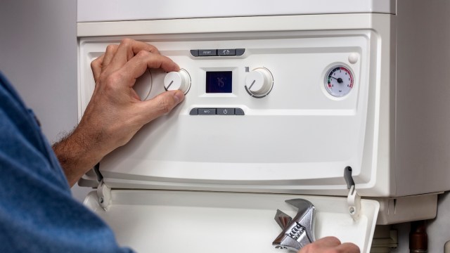 A person adjusts the temperature of a water heater.
