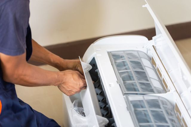 A technician fixing an AC unit.