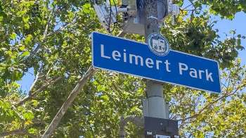 A street sign for Leimert Park surrounded by green foliage.