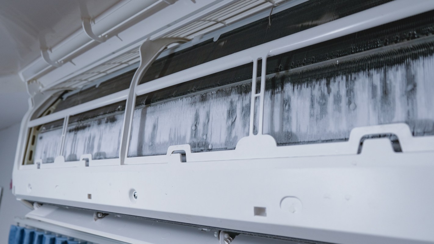 An air conditioning unit with visible ice buildup on the internal components.