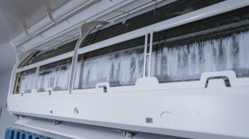 An air conditioning unit with visible ice buildup on the internal components.