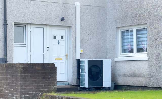 A front door with two windows and an air conditioning unit on a textured wall.