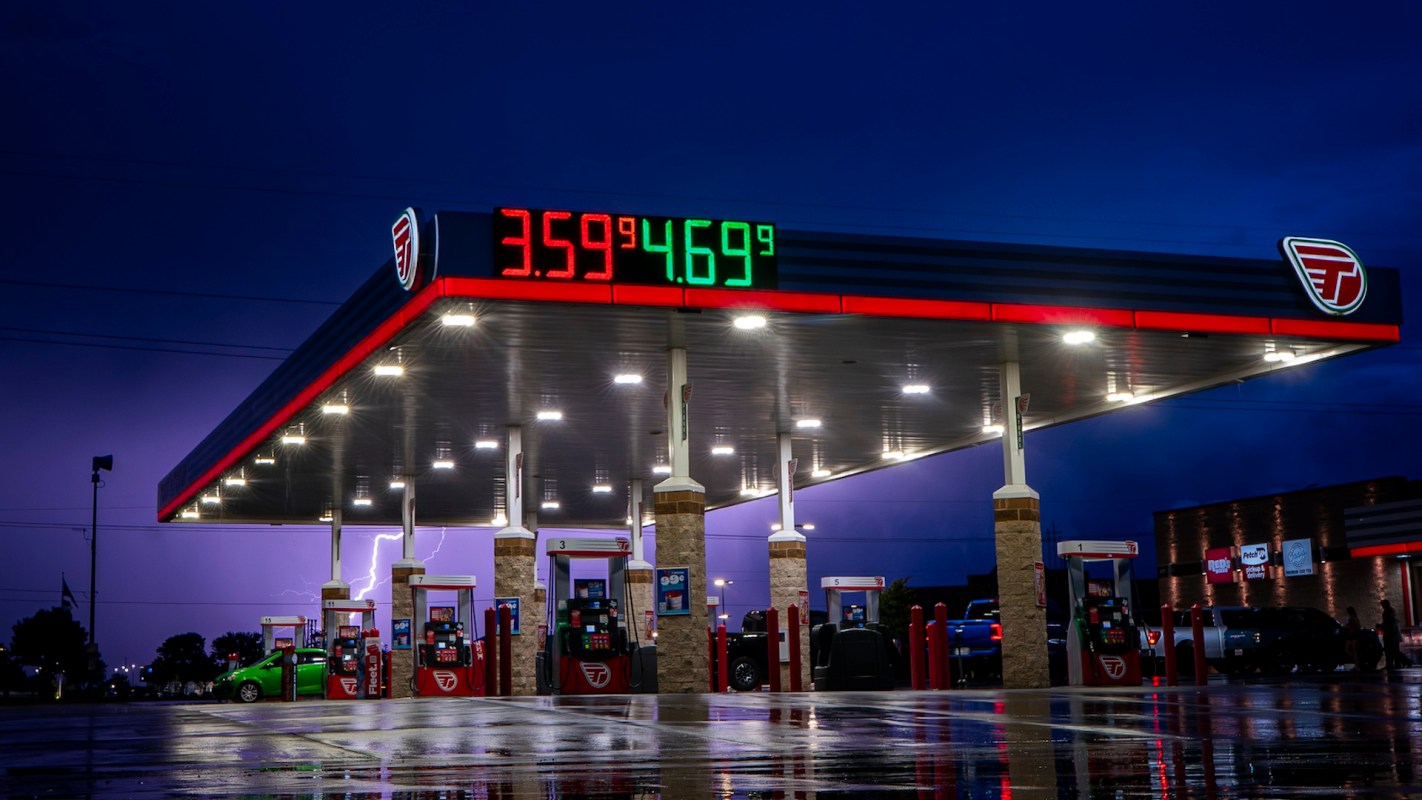 A gas station illuminated at night with a price display showing fuel prices.