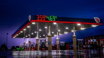 A gas station illuminated at night with a price display showing fuel prices.