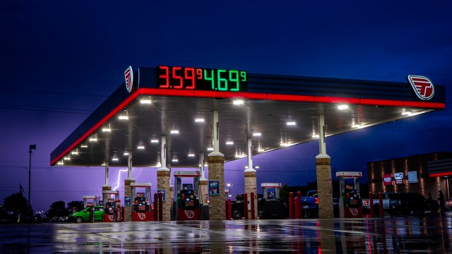 A gas station illuminated at night with a price display showing fuel prices.
