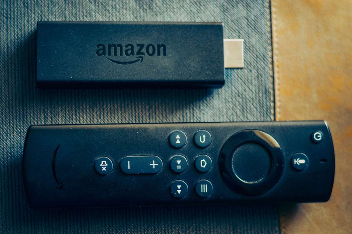 An Amazon Fire TV Stick and remote on a textured surface.