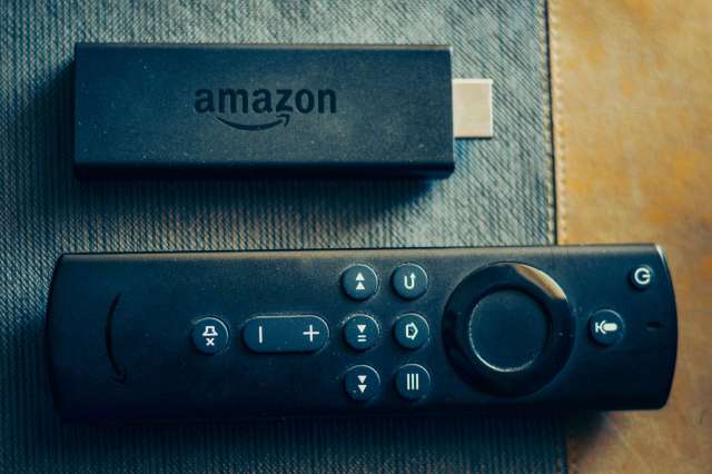 An Amazon Fire TV Stick and remote on a textured surface.
