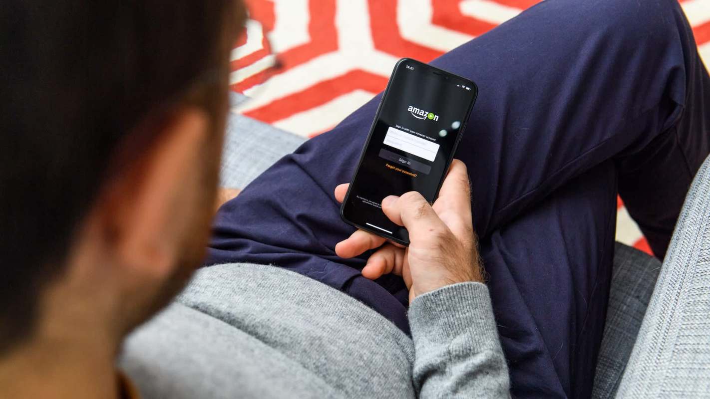 A person using a smartphone to access the Amazon login screen while seated.
