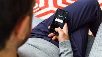 A person using a smartphone to access the Amazon login screen while seated.