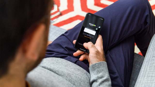 A person using a smartphone to access the Amazon login screen while seated.