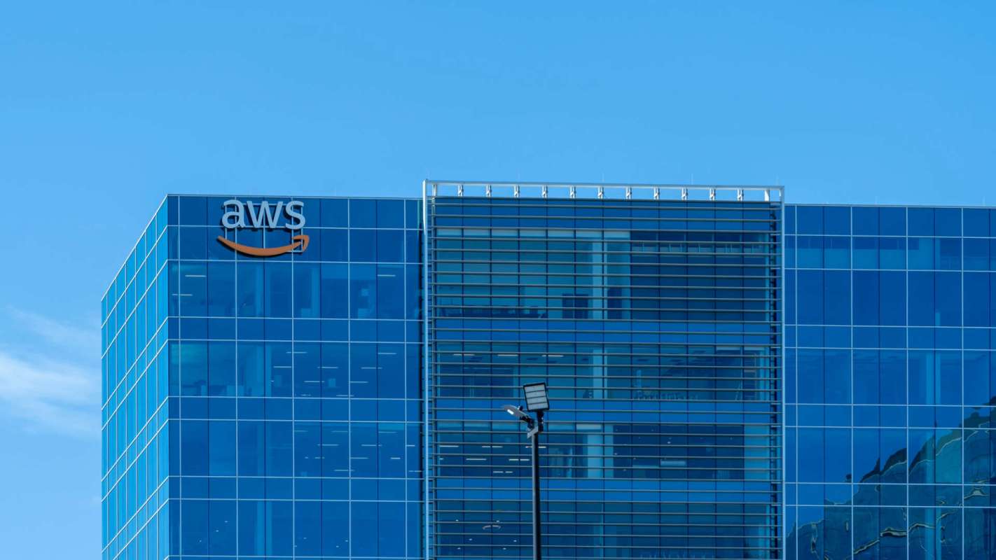 An office building with large glass windows and an AWS logo on the facade.